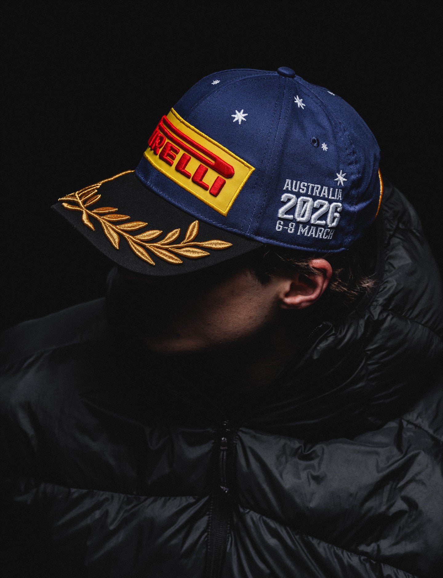 Person wearing a blue cap with red and yellow branding on a black background