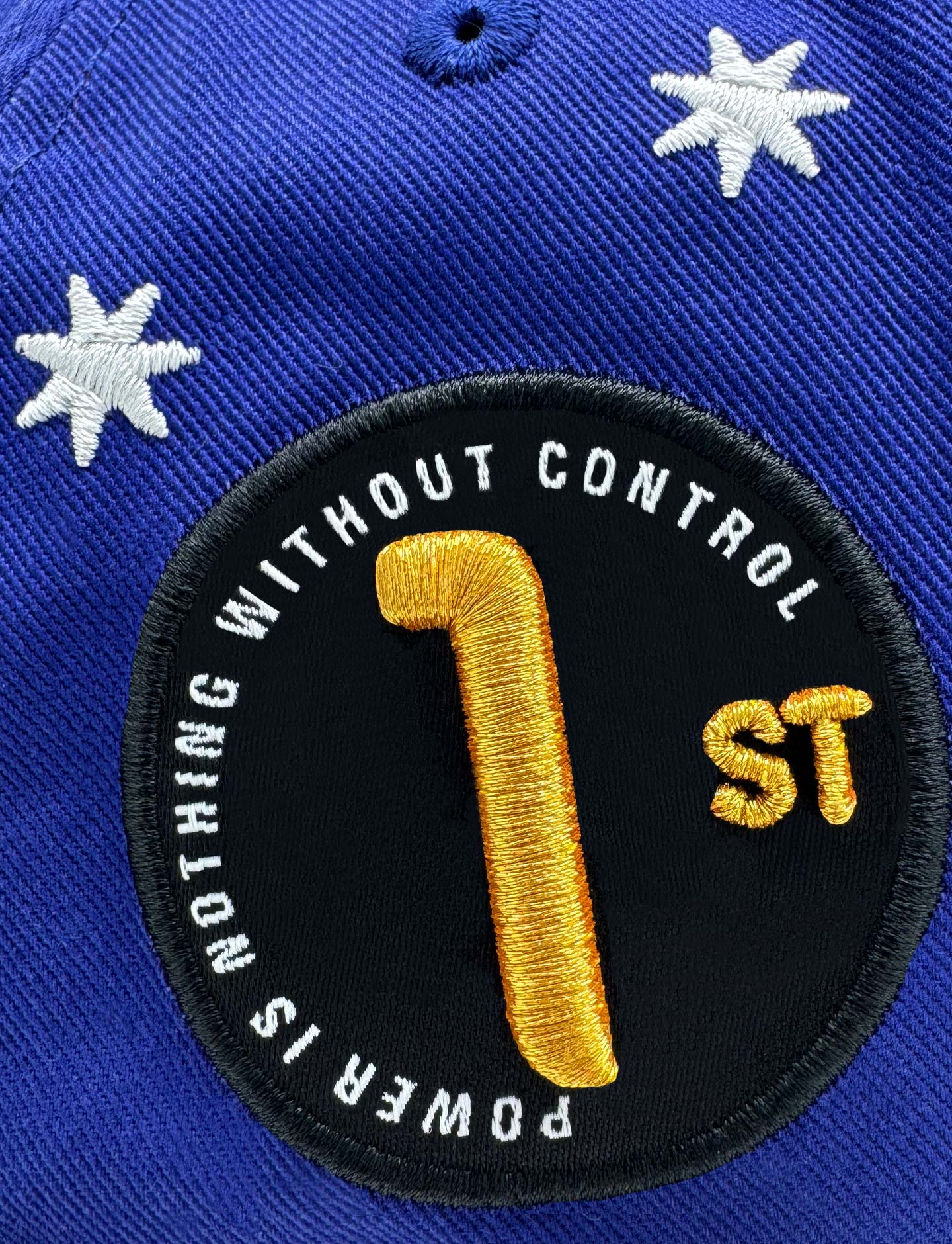 Blue cap with a black patch featuring yellow text and number '1st'.