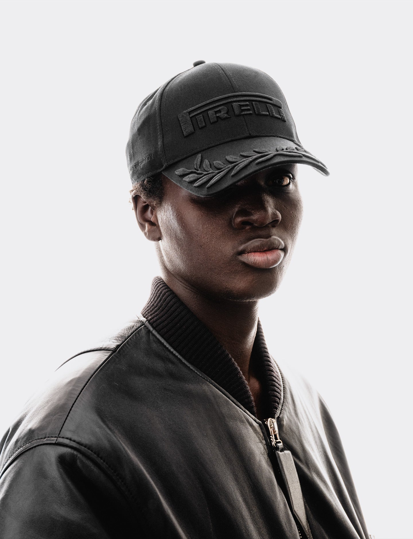 Person wearing a black cap with Pirelli branding on a light gray background