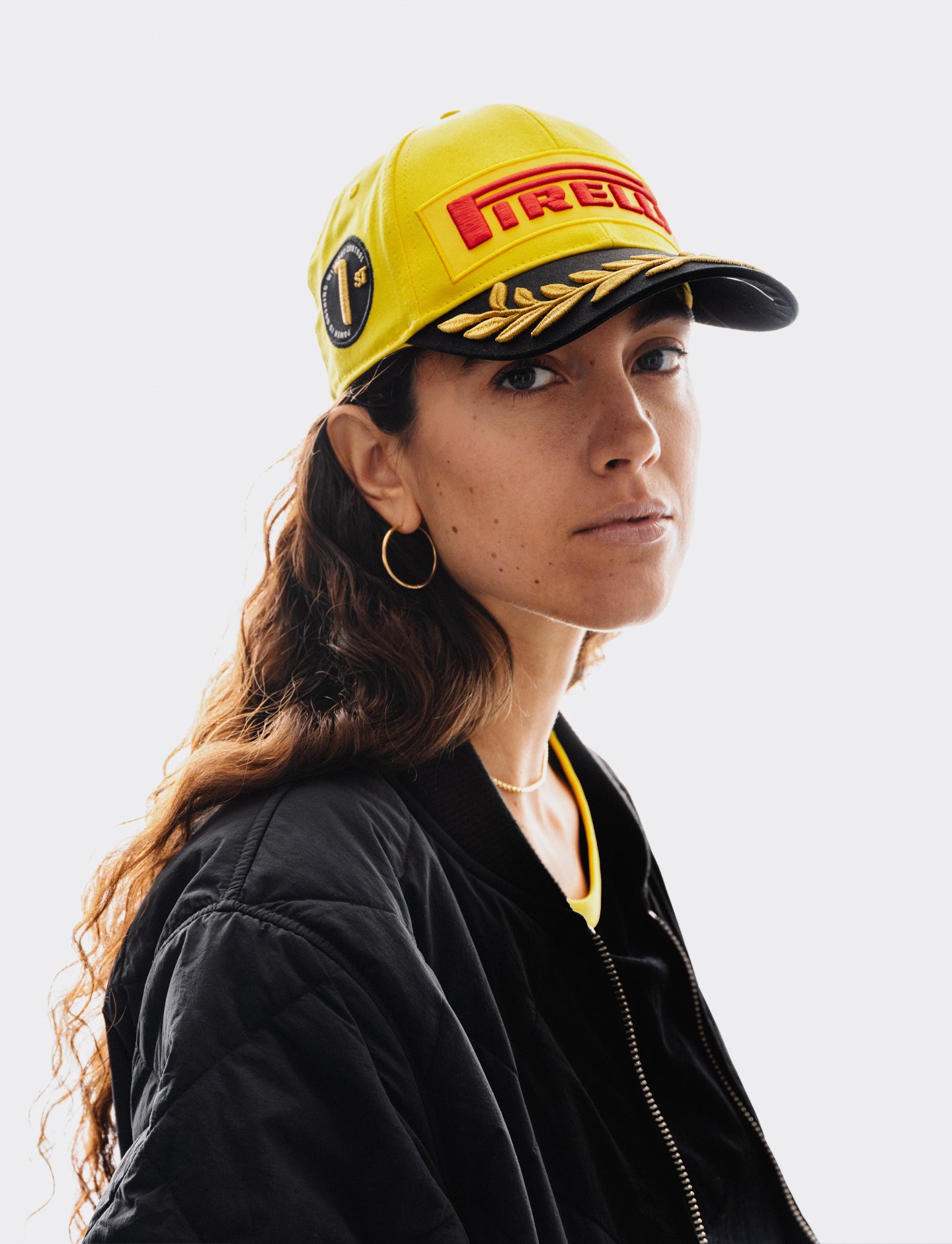 Person wearing a yellow Pirelli cap with a logo on a white background
