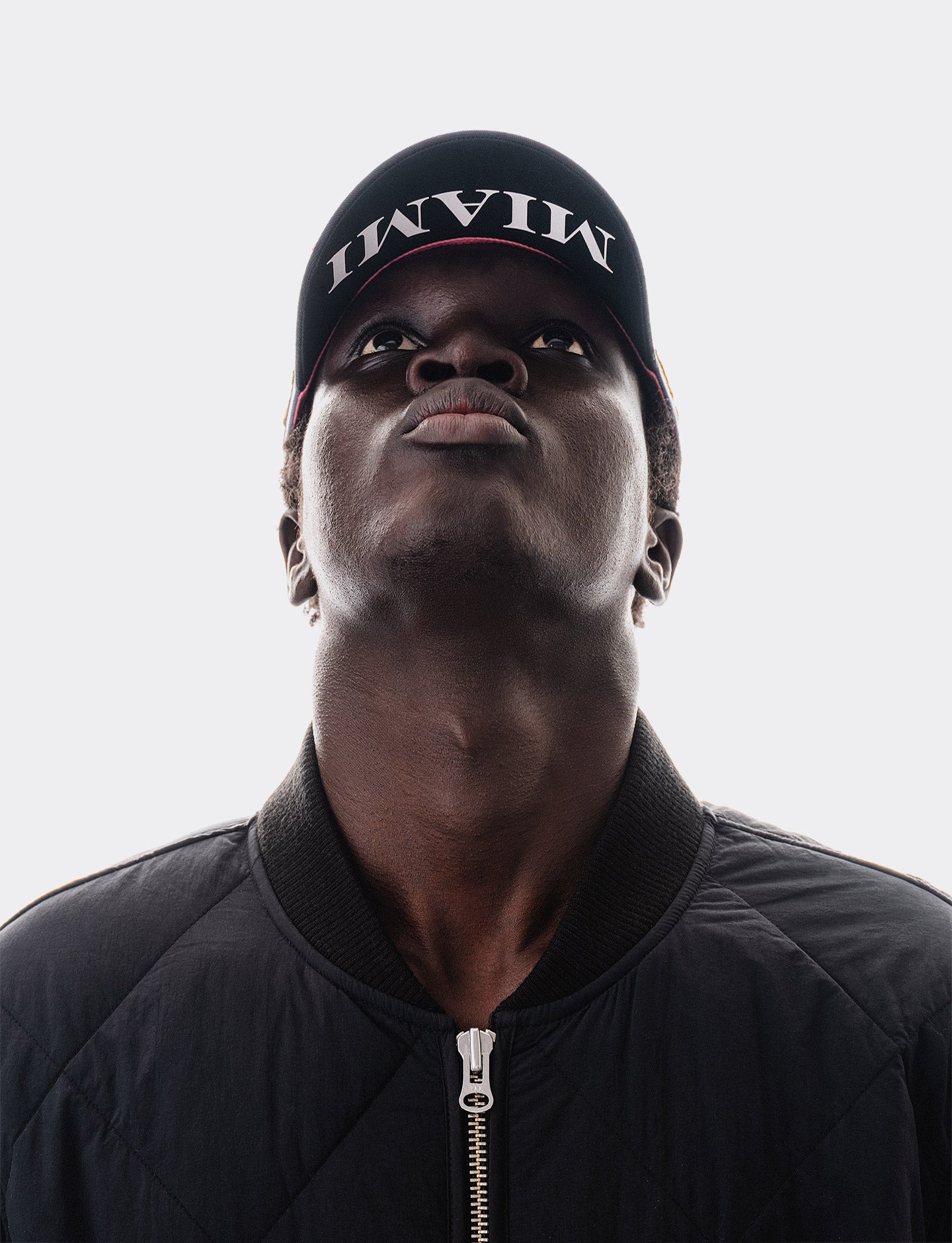 Person wearing a black cap with 'Miami' text on a light gray background