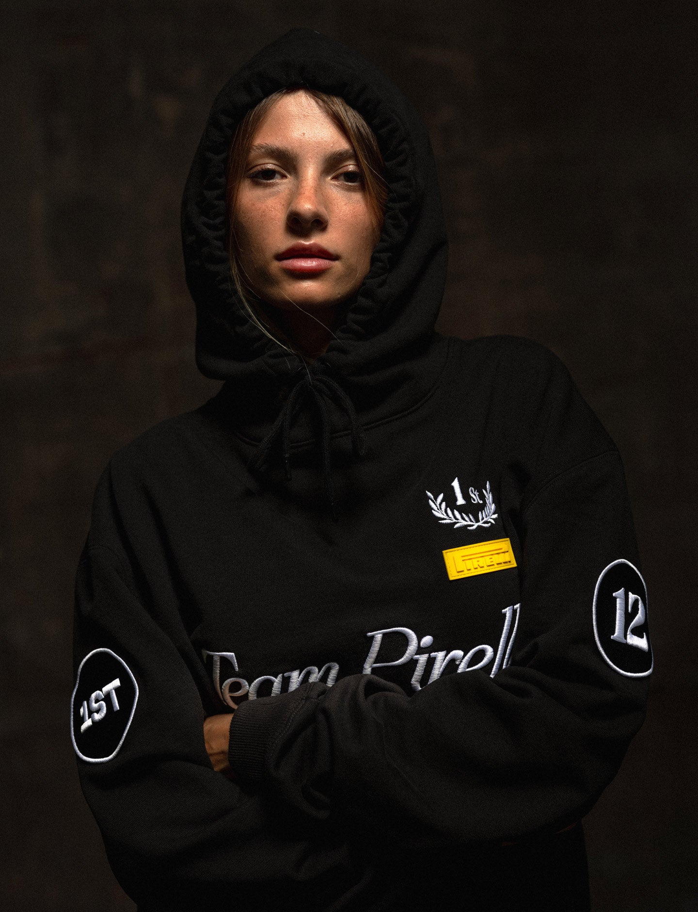 Person wearing a black Pirelli hoodie with branding on a dark background