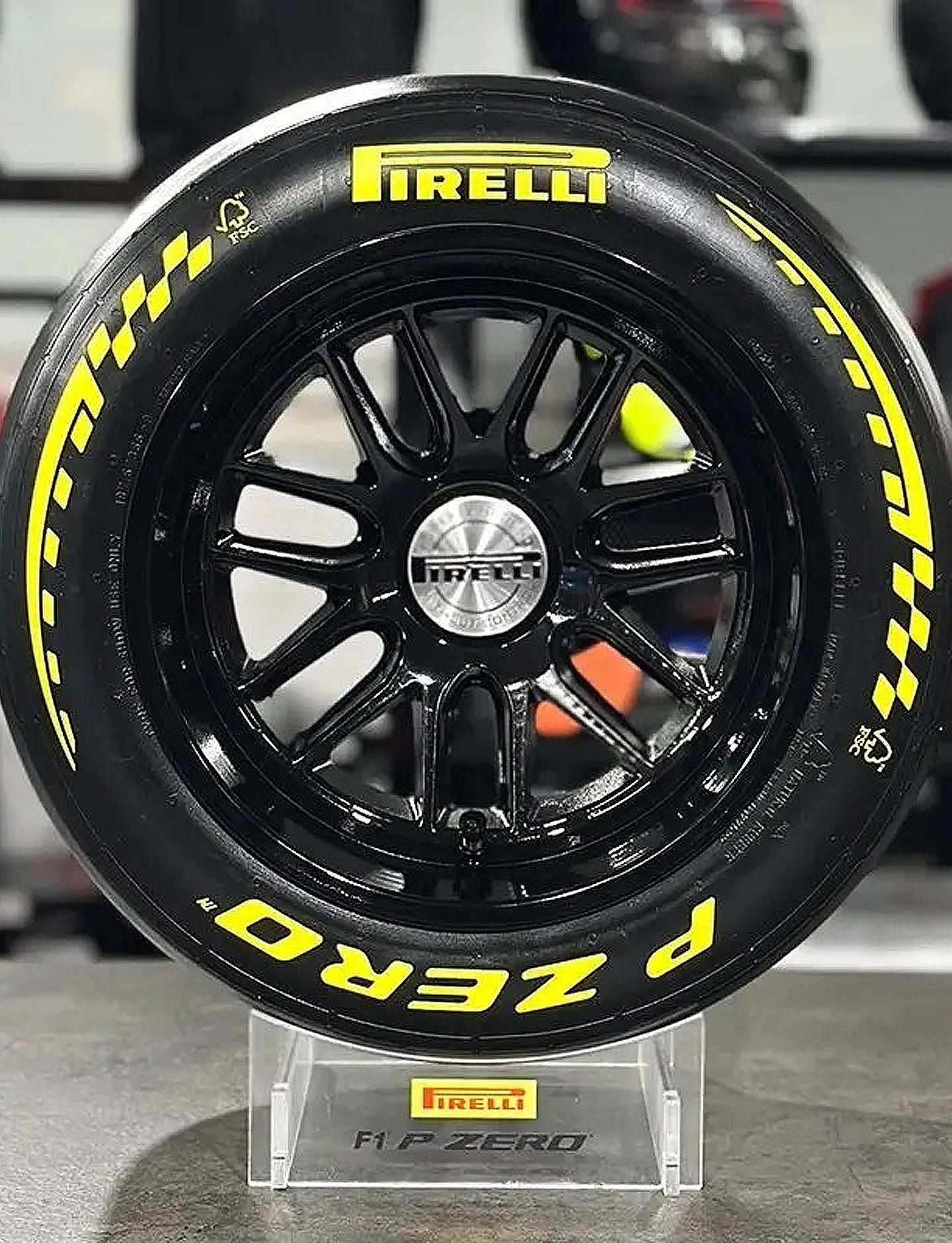 Pirelli tire with yellow lettering on a black rim, displayed on a stand.
